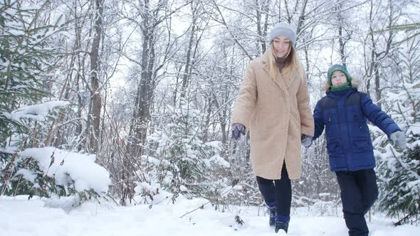 Mother and Son Walking in Snowy Forest