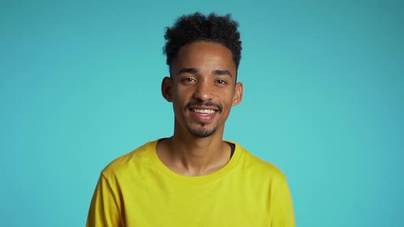 Handsome african american man with trendy curly hairdo on blue studio background