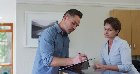 Caucasian man talking and signing documents at reception at modern dental clinic