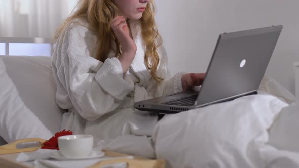 Lady Drinking Coffee and Working on Laptop in Hotel Room During Business Trip