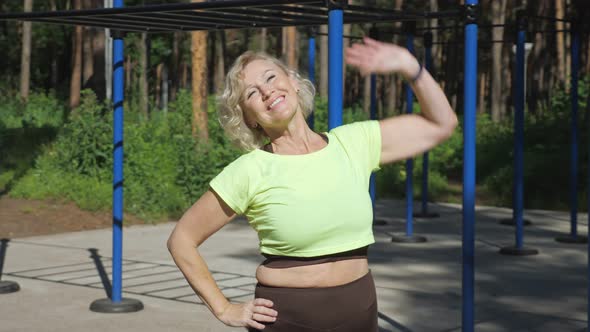 Adult Woman Makes Back Stretching Exercises on Sport Ground