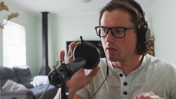 Focused caucasian man wearing headphones, talking and recording