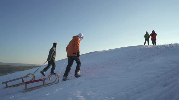 Active Senior Couples Enjoying Winter Day Outdoors With Sled and Tea