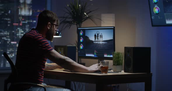 Young Man Sitting Back and Editing Video Inside a Room