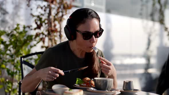 An Adult Happy Female Tourist Has Breakfast in a Street Cafe Croissant with Salmon and Coffee