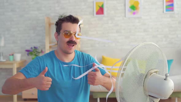 Funny Young Man in Front of a Working Electric Fan Escapes From the Heat in the Apartment Slow Mo