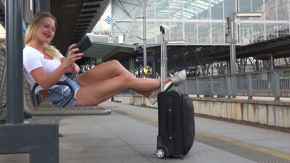 A Young Beautiful Woman Takes Selfies on a Train Station Platform