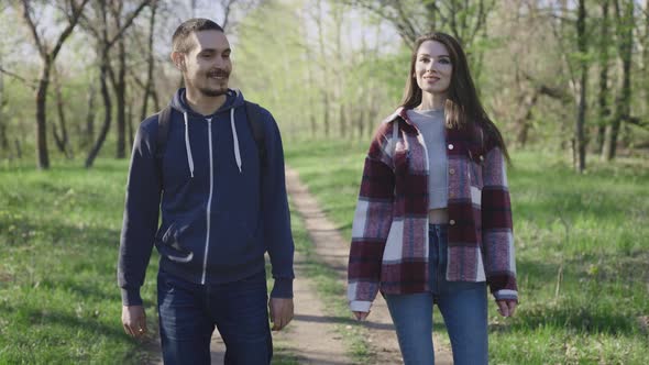 A Couple of Young People Communicate While Walking