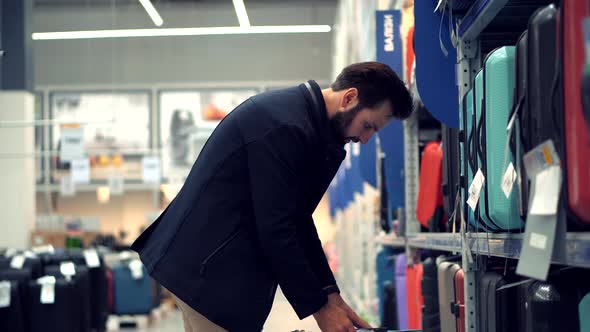 Man In Market Choosing Travel Bag. Businessman In Supermarket.Shopping In Hypermarket Mall On Travel