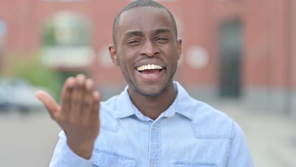 Outdoor Portrait of Young African Man Pointing Finger and Inviting