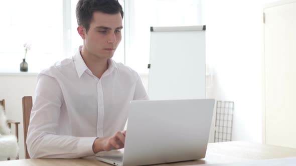 Businessman Leaving Office After Closing Laptop at Work