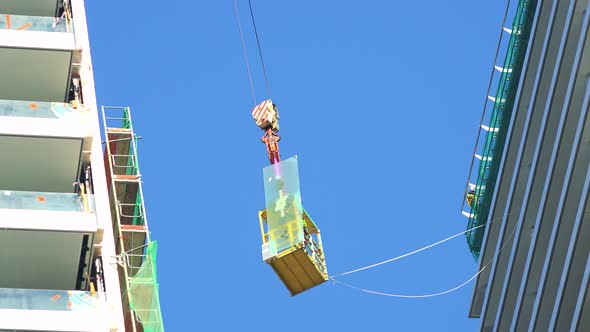 A Cabin Is Lifted Up on a Cable During a High-rise Building Construction - the Clear Blue Sky