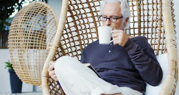 Senior man having coffee while reading a book 4k