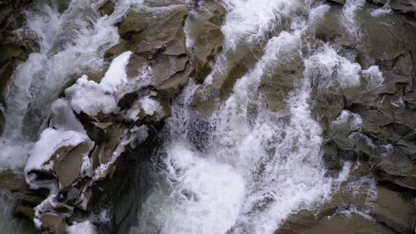 Rapid Flow of Water From a Mountain Creek and Stone Rapids with Snow in Winter. Waterfall. Slow