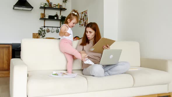 Mother Working From Home Having a Work Video Call While Her Child Distracts and Drawing Attention