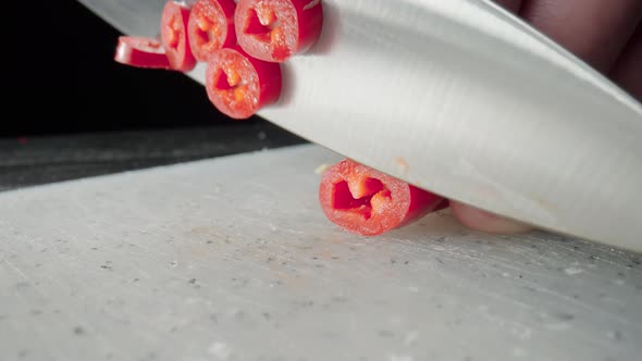 Male Hands Slicing a Red Hot Chili Pepper with a Sharp Knife