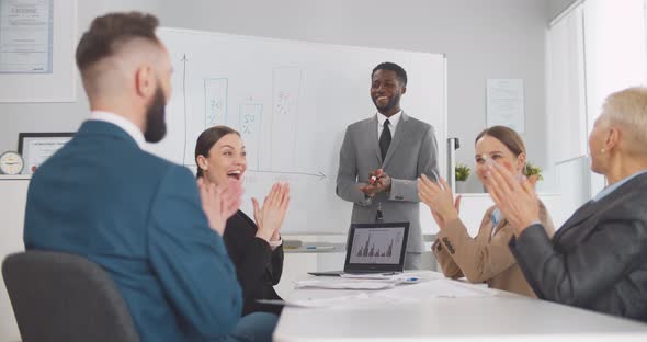 Business People Sitting in Office Applauding to African Male Colleague After Successful Presentation