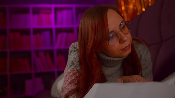 A Beautiful Student with Glasses Reading a Big Book