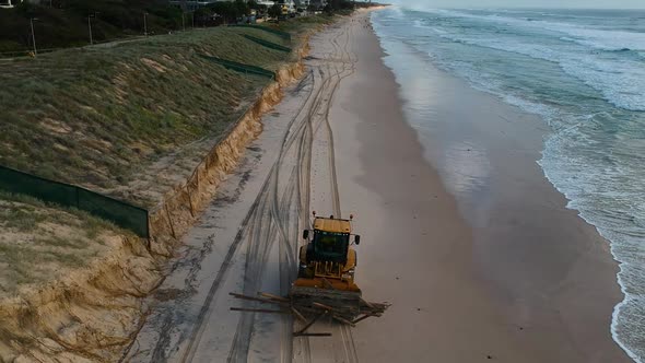 Heavy machinery picking up rubbish from a beach that was damaged by a recent cyclone swell and high