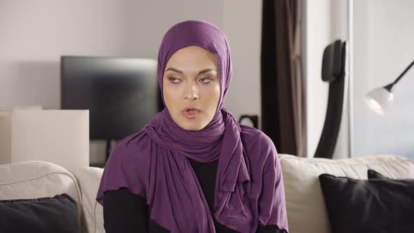 A Young Beautiful Muslim Woman is Angry As She Sits on a Sofa in an Apartment