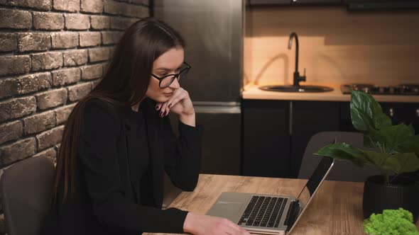 Focused Smiling Businesswoman in Glasses Using Laptop at Home Office
