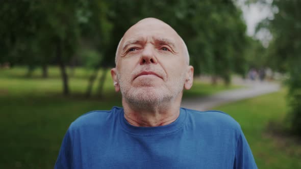 Healthy and Strong Old Man Looking in Camera Makes Breathing Practice in Park Outdoor