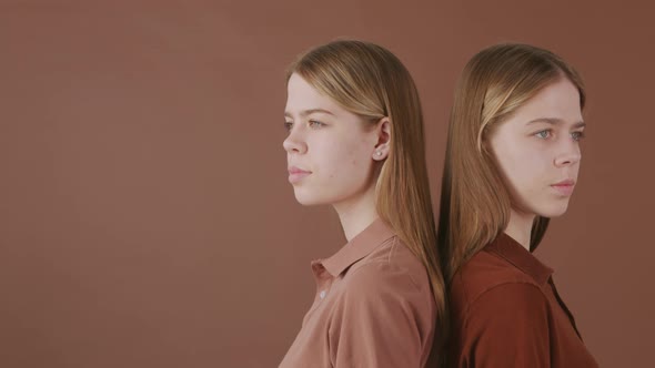 Identical Twins Standing Isolated on Brown Background