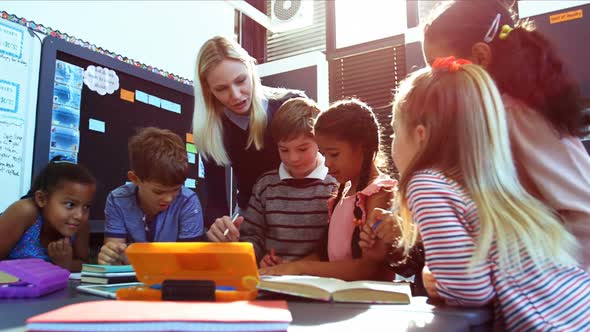 Teacher helping schoolkids with their homework in classroom