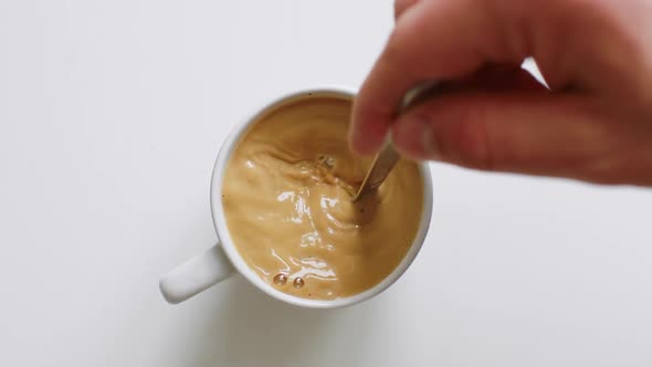 Person Hand Stirring Coffee with Spoon