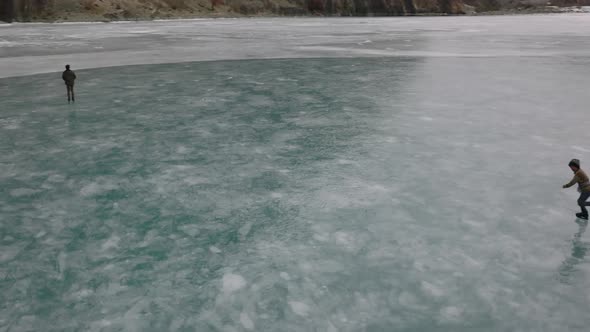 Aerial slow motion shot of alone kid skating over ice at Khalti Pakistan. Rising shot.