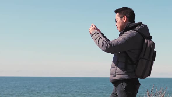Man taking photo of ocean with smart phone