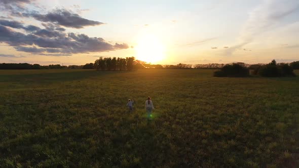 The Mother and Boy Run with a Kite on a Green Field