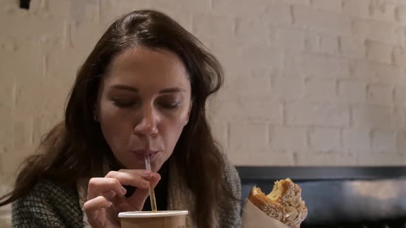 Young Woman Eating Delicious Baked Croissant and Drink Tea in Cafe