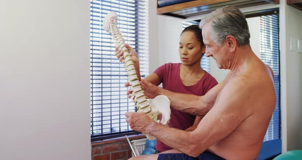 Physiotherapist explaining the spine model to senior patient 4k