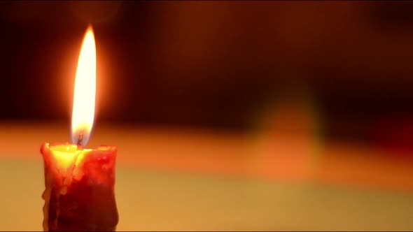 Single candle flickers against dark background