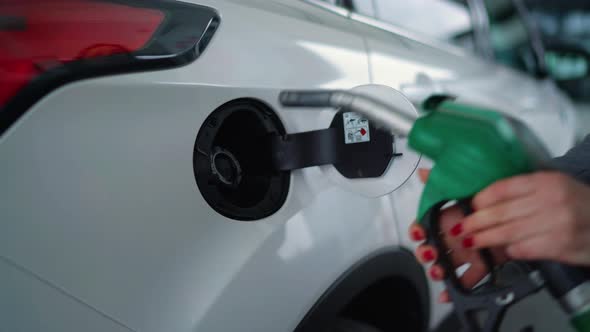 Woman Fills Petrol Into Her Car at a Gas Station Closeup