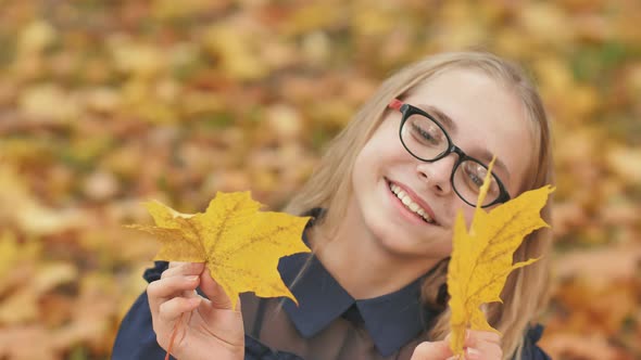 A Young Girl of 13 Years Old with Autumn Leaves Poses in Front of a Video Camera.