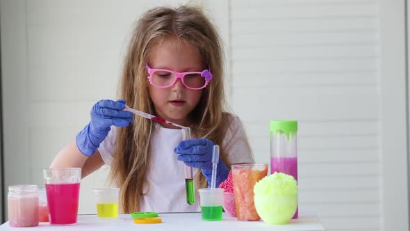 A little girl in pink glasses conducts experiments.