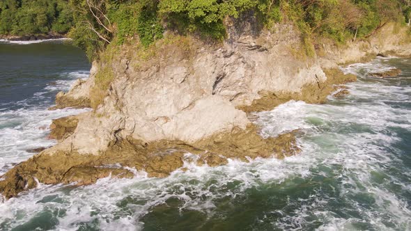 Waves crashing onto the rough cliffs of the central pacific coast in Costa Rica on a sunny day. Slow