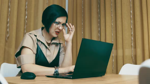 Pretty Woman Adjusting Glasses While Working with Laptop in the Office or at Home