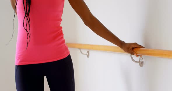 Woman stretching on barre in fitness studio 
