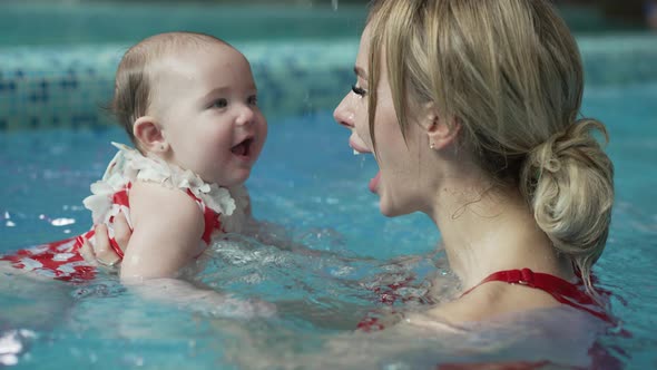 Cheerful Mother with Her Baby in the Pool