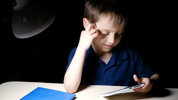 A Child Enjoys Watching a Cartoon at Home at Night Using a Smartphone and Smiling