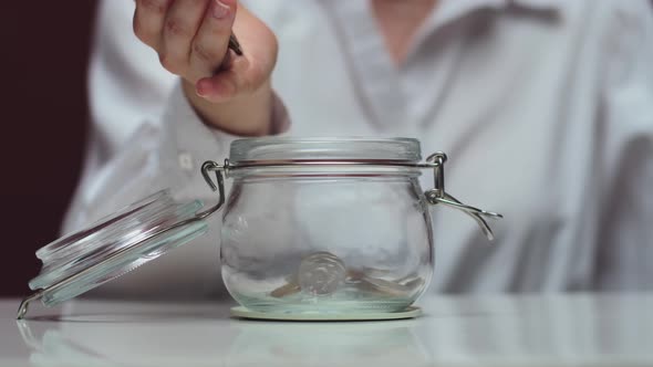 Pouring Coins Into a Jar