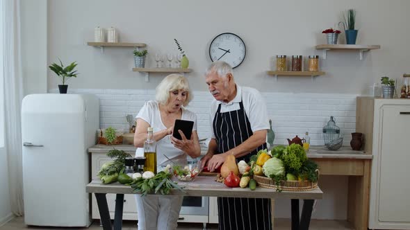 Vegan Senior Grandparents Looking for a Culinary Recipe Online on Digital Tablet, Cooking Salad