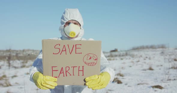 Man Wore in Protective Suit Shows Save Earth Sign on Abandoned Place in Winter