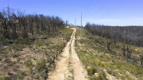 Drone aerial footage of telephone lines along a dirt track in regional Australia