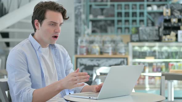 Young Man with Laptop Feeling Shocked