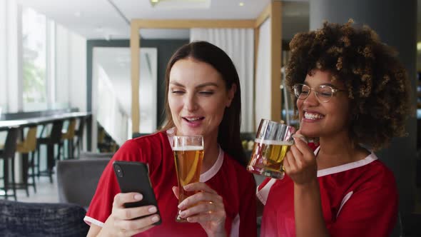 Diverse group of happy friends watching a game drinking beers and taking a selfie at a bar