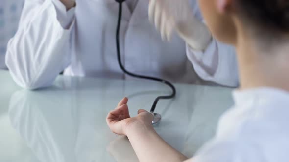 Doctor Listening to Pulse of Woman With Stethoscope, Appointment at Clinic